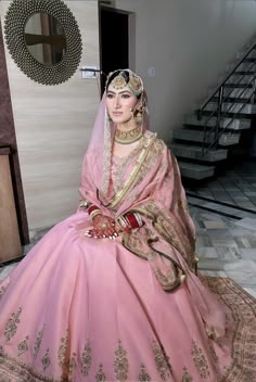 a woman in a pink bridal gown sitting on the floor next to some stairs