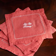 four red napkins with embroidered words on them sitting on a wooden tablecloth that says, stop honky