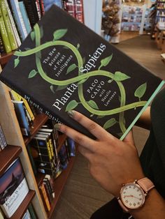 a person holding up a book in front of a bookshelf filled with books