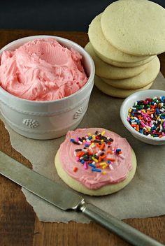 a bowl of ice cream and some cookies with sprinkles next to it