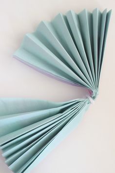 two folded paper fans sitting on top of a table