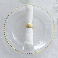 a white plate topped with a napkin and gold beaded place setting on top of a table