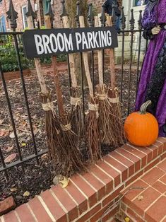 brooms are placed in front of a sign that says broom parking on the side of a brick fence