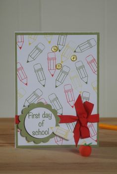 a first day of school card with pencils and an apple on the table next to it