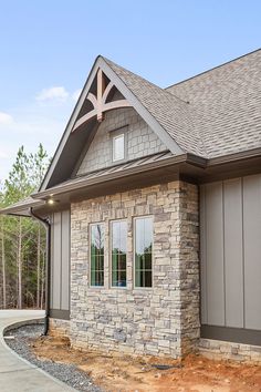 the front of a house that is being built with stone and shingled roofing