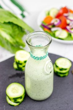 cucumber salad dressing in a glass bottle with sliced cucumbers around it