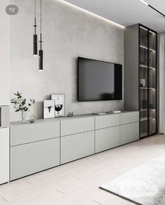 a living room with white furniture and a flat screen tv mounted on the wall above it