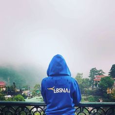 a person sitting on a bench looking out at the mountains and houses in the distance