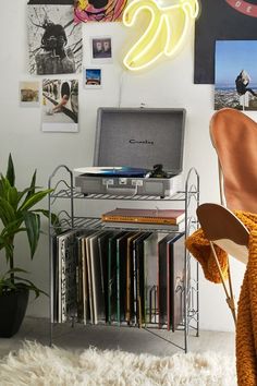 a laptop computer sitting on top of a metal shelf next to a pile of records