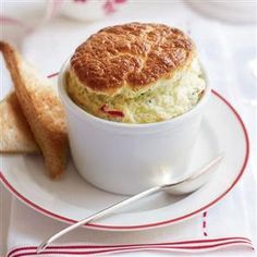 a white bowl filled with food on top of a plate next to a piece of bread