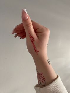 a woman's hand with a tattoo on her left wrist and the word love is written in red ink