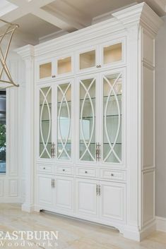 a white china cabinet with glass doors and gold accents in a large living room area