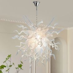 a white chandelier hanging from the ceiling in a room with plants and potted plant