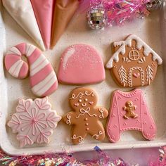 decorated cookies in a tray with pink and white decorations on it, including gingerbreads