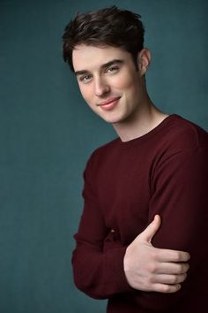 a man in a red sweater posing for a photo with his arms crossed and looking at the camera