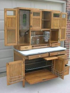 an old fashioned wooden cabinet with glass doors on the front and bottom shelves, in front of a garage door