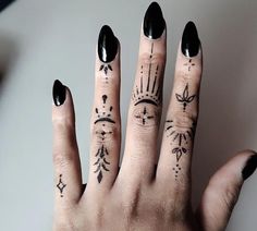 a woman's hand with black nail polish and tattoos on her fingers, showing the ring finger tattoo design