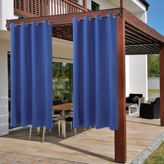 an outdoor dining area with blue curtains on the outside wall and wooden patio furniture in the background