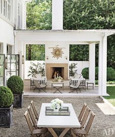 an outdoor dining area with chairs, table and fire place in the middle of it