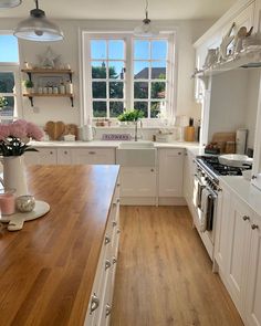 a kitchen with wooden floors and white cabinets is pictured in this image, there are flowers on the counter