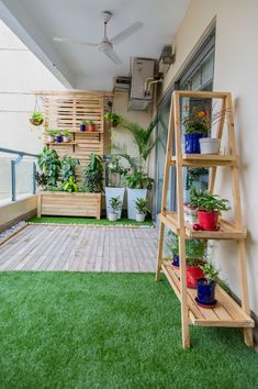 a small balcony with plants and potted plants on the grass in front of it