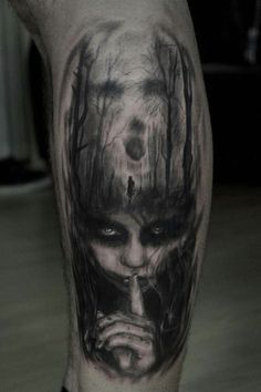 a man's leg with a black and grey tattoo on it that has a creepy face in the woods