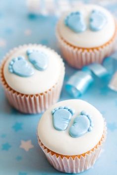 three cupcakes with white frosting and blue decorations