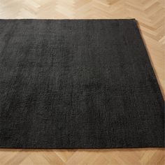 a black rug is on the floor in an empty room with parquet wood floors