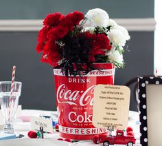 a coca - cola can centerpiece with flowers in it on top of a table