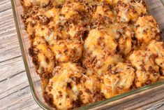 a casserole dish with cheese and meat in it on a wooden table top