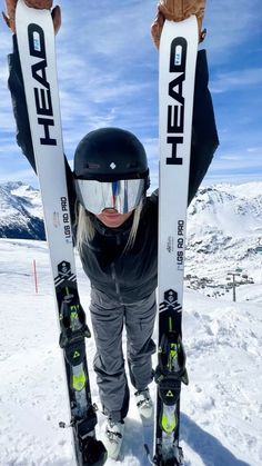 a woman standing in the snow holding up her skis