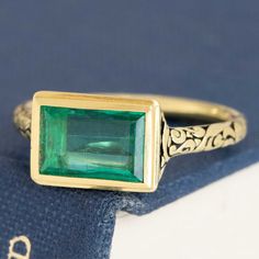 This antique-inspired emerald bezel ring is a bold beauty, bringing tons of color and charm to your ring collection. The chunky gold bezel hugs that Colombian emerald and emphasizes her geometric edges - the darkened engraved shoulders give a Renaissance vibe which we're also quite fond of. The stone sits in the East/West orientation, allowing for maximum spread across the top of the finger. 18kt yellow gold Size 6.25 & resizable Measures: 9.05 x 6.08 x 2.86mm GIA Report Here Please see qualitat Art Deco Green Jewelry With Bezel Setting, Green Art Deco Jewelry With Bezel Setting, Yellow Gold Emerald Signet Ring With Bezel Setting, Rectangular Gold Emerald Ring With Bezel Setting, Art Deco Emerald Ring With Bezel Setting, Art Deco Emerald Jewelry With Bezel Setting, Art Deco Emerald Cut Ring With Bezel Setting, Gold Emerald Cut Art Deco Ring, Gold Emerald Ring In Art Deco Style