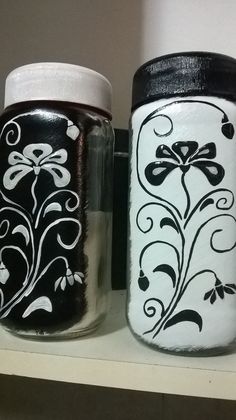 two jars with designs painted on them are sitting on a shelf next to each other