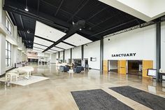 an empty room with couches, tables and chairs on the floor in front of large windows