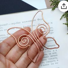 a hand holding a piece of metal wire in front of an open book with blue flowers