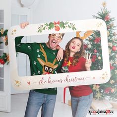 a man and woman holding up a christmas photo frame with the words the brown's christmas written on it