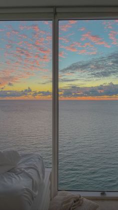 an ocean view is seen through two large windows with the sun setting over the water