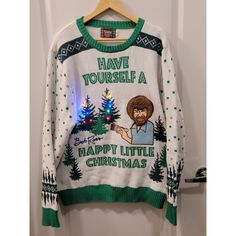 a sweater that says have yourself a happy little christmas on the front and back with an image of bob ross