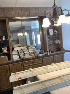 a large mirror sitting above a dresser next to a shelf with books on top of it