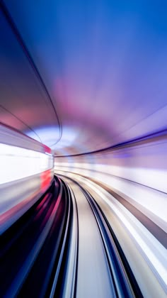 a blurry photo of a train going through a tunnel with blue sky in the background