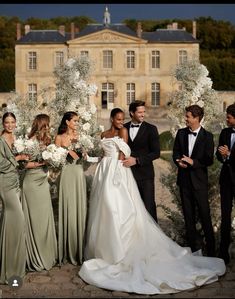 a group of people standing next to each other in front of a building with flowers