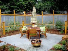 an outdoor patio with table, chairs and umbrella in the center surrounded by wood fencing