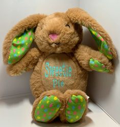 a stuffed animal with polka dots on it's ears and feet, sitting against a white wall