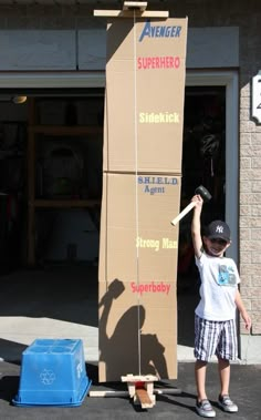 a young boy standing next to a giant cardboard box with a skateboard on it