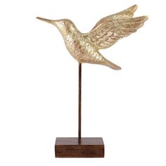 a gold bird statue on a wooden base with a white background and brown wood base