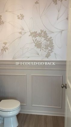 a white toilet sitting in a bathroom next to a wall with flowers painted on it