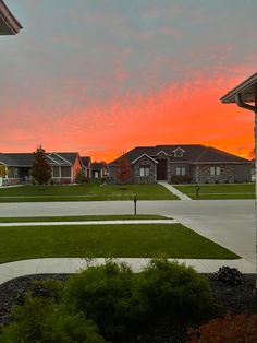 the sun is setting over some houses and lawns in an area with green grass