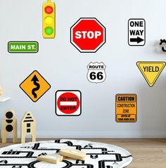 various traffic signs are on the wall next to a toy car and wooden blocks in front of it