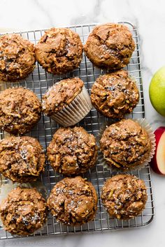 muffins on a cooling rack next to an apple and some other food items