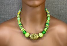 This 20" necklace feels like the green grass of an African summer. It is designed with various handmade Ghana glass beads in shades of green with a large 'basket weave' brass focal bead from Côte d'Ivoire. It has a large brass lobster cloth glass with extension chain for ease of use and positioning on the neck. These beads are all handmade in Africa by crafts people who have been creating these beads for centuries. This creates a sustainable business for many African families using a completely recycled green product. The organic feel of these beads creates a beautiful piece of one of a kind, wanderlust jewelry. This necklace can be paired with many styles of clothing and is perfect for both day and evening wear. It makes a wonderful gift for the woman who Likes to collect unique jewelry p Traditional Green Adjustable Necklace, Traditional Green Beaded Necklace With Large Beads, Adjustable Green Beaded Necklace, Unique Green Adjustable Necklace, Green Spiritual Beaded Necklace With Colorful Beads, Green Large Beaded Glass Necklaces, Green Glass Beaded Necklace With Large Beads, Bohemian Green Czech Glass Beads, Spiritual Green Necklaces With Colorful Beads